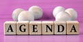 AGENDA - word on wooden cubes on pink background with wooden round balls