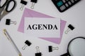 Agenda the word is written on a white sheet of paper, pens, scissors, a magnifying glass, paper clips lie next to Royalty Free Stock Photo