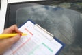 An agent draws up documents for broken windshield in car. Royalty Free Stock Photo