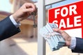 Agent Handing Over Keys as Buyer is Handing Over Cash for House with Home and For Sale Real Estate Sign Behind. Royalty Free Stock Photo