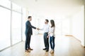 Agent Shaking Hands With Man By Woman In New Home Royalty Free Stock Photo