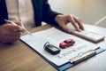 Agent is signing the insurance contract for the car at the document on the desk Royalty Free Stock Photo