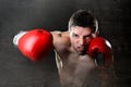 Aggressive boxer man boxing in fighting gloves throwing angry right hook punch Royalty Free Stock Photo