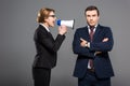 aggressive businesswoman with bullhorn yelling at businessman,