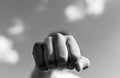 Aggressive caucasian teenage boy showing hes fist to the camera outdoors monochrome image