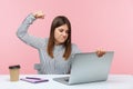 Aggressive depressed brunette woman raising fist ready to kick laptop display sitting at workplace, unhappy dissatisfied with work