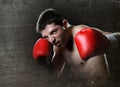 Aggressive fighter man training shadow boxing with red fighting gloves throwing vicious left hook punch Royalty Free Stock Photo