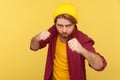 Aggressive hipster bearded guy in beanie hat, checkered shirt holding clenched fists up ready to boxing Royalty Free Stock Photo