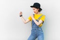 Aggressive hipster woman in overalls, T-shirt and hat, keeps fists clenched, being ready to fight. Royalty Free Stock Photo