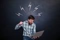 Aggressive man going to break laptop over chalkboard background Royalty Free Stock Photo