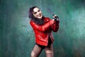 Aggressive punk woman strike someone with a bat, in red leather jacket Royalty Free Stock Photo