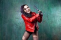 Aggressive punk woman strike someone with a bat, in red leather jacket