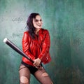 Aggressive punk woman strike someone with a bat, in red leather jacket