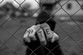 Aggressive teenage boy holding the wired fence at the correctional institute, the word hate is written on hes hand Royalty Free Stock Photo