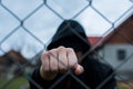 Aggressive  teenage boy showing hes fist behind wired fence at the correctional institute,  focus on the boys hand Royalty Free Stock Photo