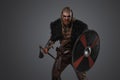 Aggressive viking with shield and axe dressed in black fur