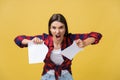 Aggressive young caucasian woman tears contract or white sheet of paper. Isolated over yellow background. Royalty Free Stock Photo