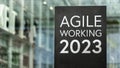 Agile working 2023 on a sign outside a modern glass office building