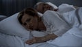 Aging couple lying sleepless in bed, woman turned back to man, resentment Royalty Free Stock Photo