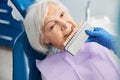 Aging female checking her teeth colour with shade scale Royalty Free Stock Photo