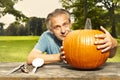 Aging man in city park working on helloween pumpkin Royalty Free Stock Photo