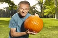 Aging man in city park working on helloween pumpkin Royalty Free Stock Photo