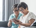 Aging society concept with Asian elderly senior adult women twin sisters using mobile digital tablet application technology