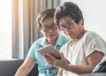 Aging society concept with Asian elderly senior adult women twin sisters using mobile digital tablet application technology