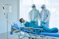 Aging woman patient infected with CORONA VISRUS or COVID-19 and two medical staffs is standing beside patient bed in ICU and