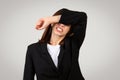 Agitated young businesswoman in a black blazer covering her eyes with her arm Royalty Free Stock Photo