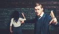 Agitated young professor with stylish mustache and beard pointing book at students in classroom while showing formula