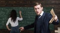 Agitated young professor teaching math at college. Brunette female student solving equation on green board Royalty Free Stock Photo