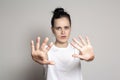 An agitated young woman put his palms forward as protection, calming someone down and looking anxiously at the camera. Isolated on Royalty Free Stock Photo