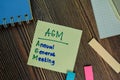 AGM - Annual General Meeting write on sticky notes isolated on Wooden Table