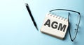 AGM text written on a notepad on the blue background Royalty Free Stock Photo