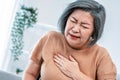 An agonizing elderly woman is experiencing chest pain.