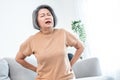 An agonizing senior woman experiencing back pain.