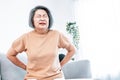 An agonizing senior woman experiencing back pain.