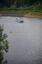 Agrement passanger boat cruising on a natural lake. Couple of people in a yellow kayak between