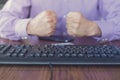 Agression in the Internet, man sitting behind keyboard with hands fists clenched