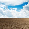 Agricultural black plowed field and clouds