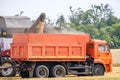 An agricultural combine harvester unloads wheat in a truck in a summer field