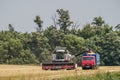 An agricultural combine harvester unloads wheat in a truck in a summer field