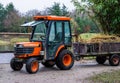 Agricultural equipment, orange tractor with a trailer that is filled with hay, farm machinery Royalty Free Stock Photo