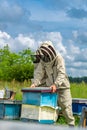 Agricultural farming in beekeeping field. Pretty woman beekeeper in protective suit.