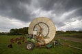 Agricultural farming irrigation hose on reel under dark clouds