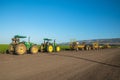 Agricultural field of celery plant and agricultural machines. Tractors at sunset, standing on the road after working day close to Royalty Free Stock Photo