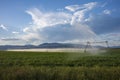 An agricultural field growing barley gets watered by a pivoting irrigation system Royalty Free Stock Photo