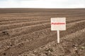 Agricultural field with rows of planted potatoes and a sign with the inscription