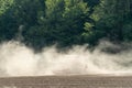 In the agricultural field, sowing equipment works. The tractor drives through the field leaving behind a cloud of thick dust. Arid Royalty Free Stock Photo